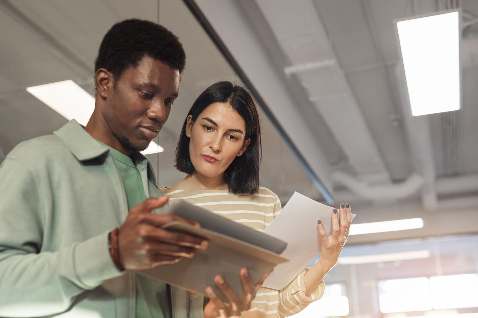 Two professionals collaborating on a project using a digital tablet in a modern office setting.