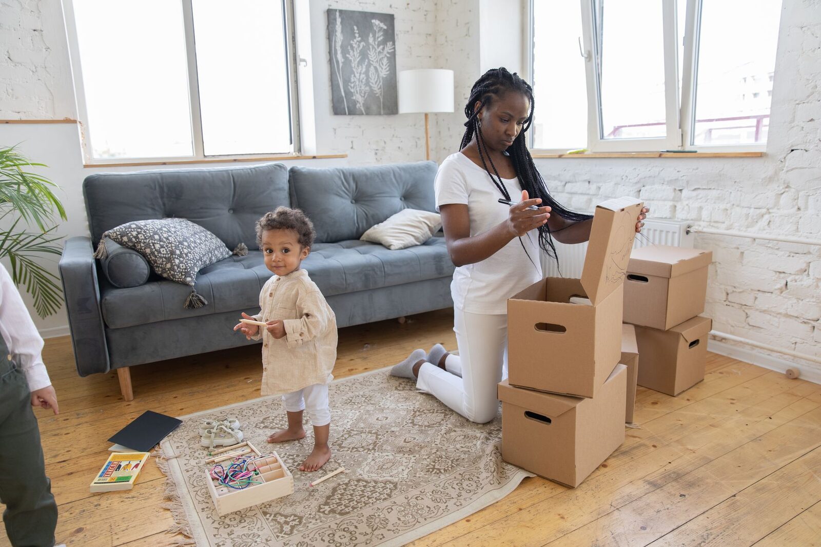 Mother and child packing boxes in a bright, modern living room.